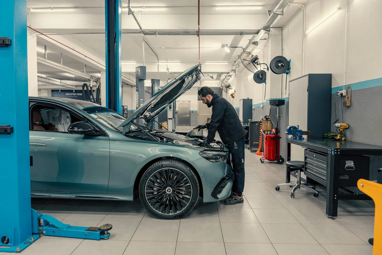 Ein Mechaniker arbeitet in einer hellen Werkstatt am Motor eines Autos.